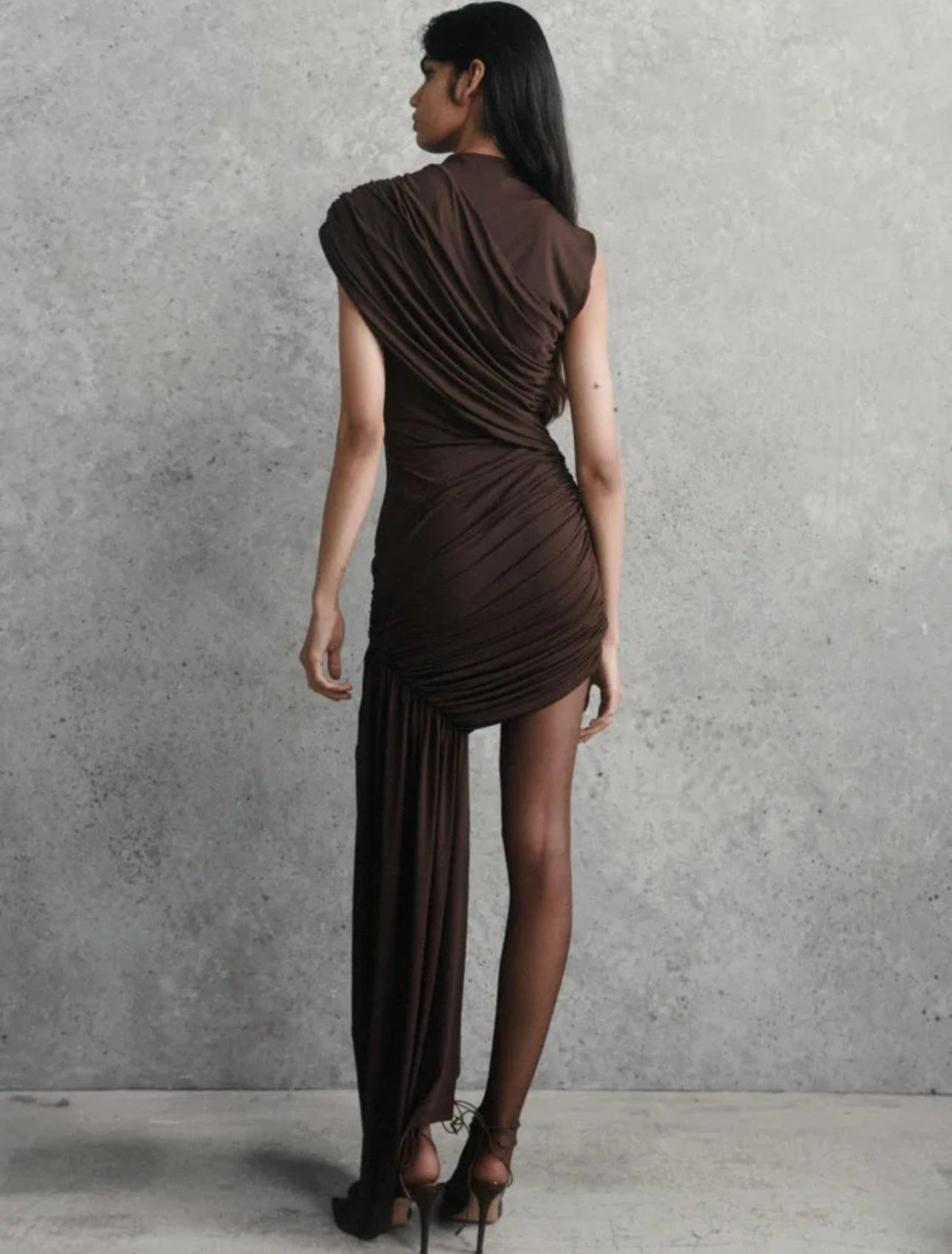 Model trägt das braune Abendkleid, Rückenansicht, figurbetont geschnitten.