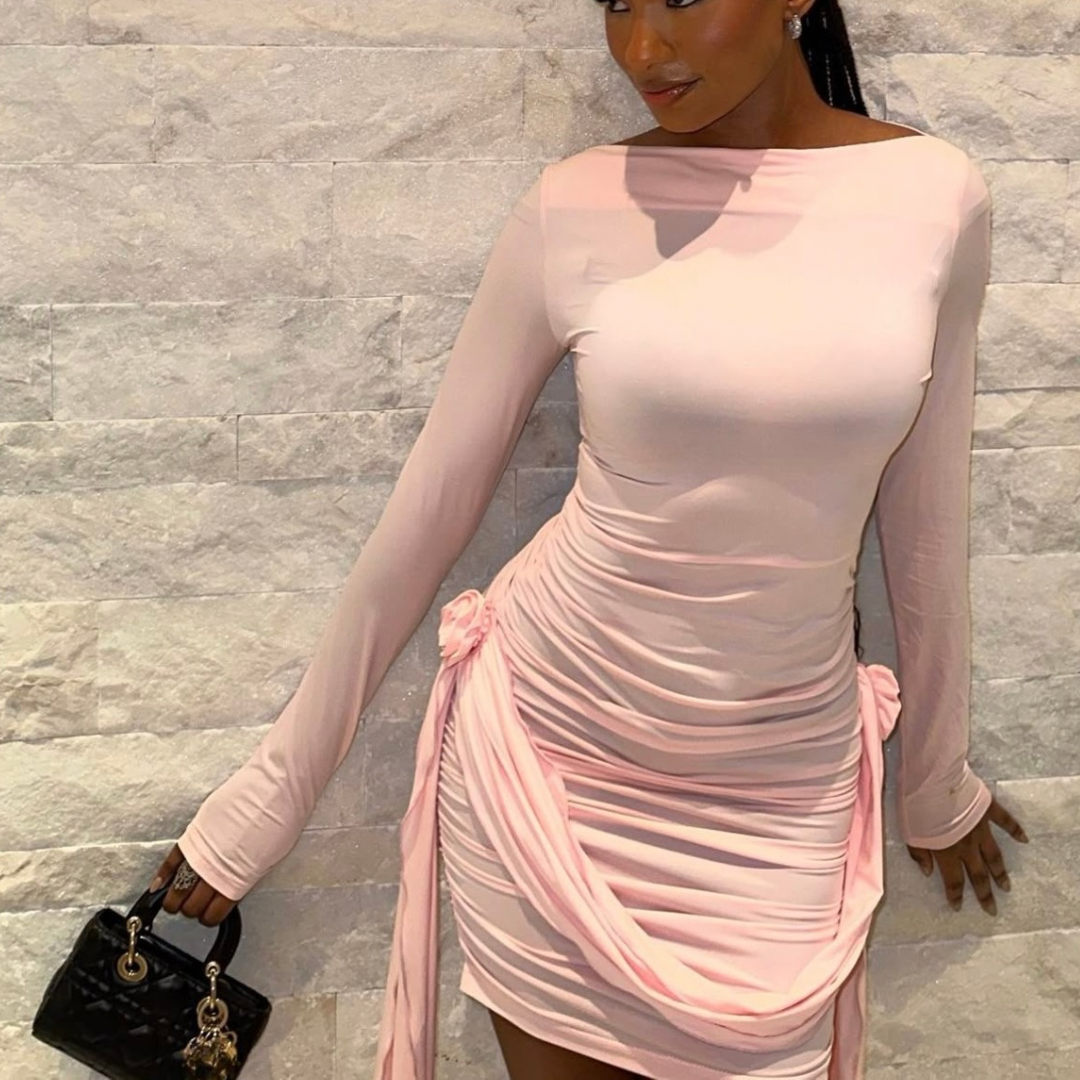 Modell trägt zartrosa Off-Shoulder-Minikleid mit Drapierung und seitlicher Raffung – figurbetonte Passform und eleganter, femininer Look