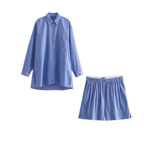Zweiteiliges Set bestehend aus hellblauem, langärmligem Hemd mit Knopfleiste und passender Shorts mit elastischem Bund, freigestellt auf weißem Hintergrund.