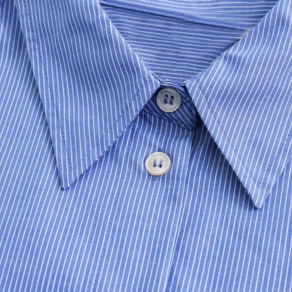 Nahaufnahme des Kragens und der Knopfleiste des blau-weiß gestreiften Damenhemds mit weißen Knöpfen und klassischem Schnitt